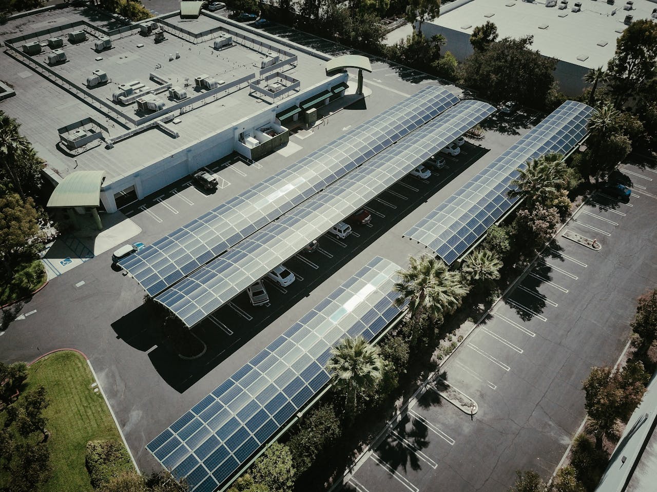 about-us-01 Aerial view of solar panels on a parking lot roof, showcasing renewable energy.
